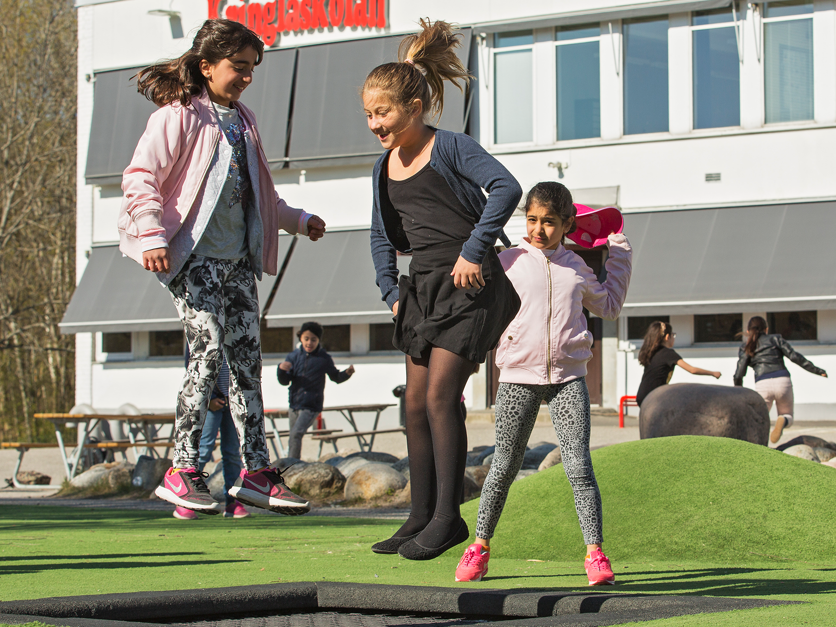Elever som hoppar på studsmatta på skolgården