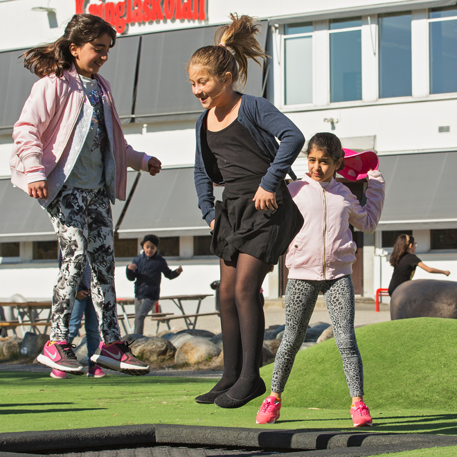 Elever som hoppar på studsmatta på skolgården