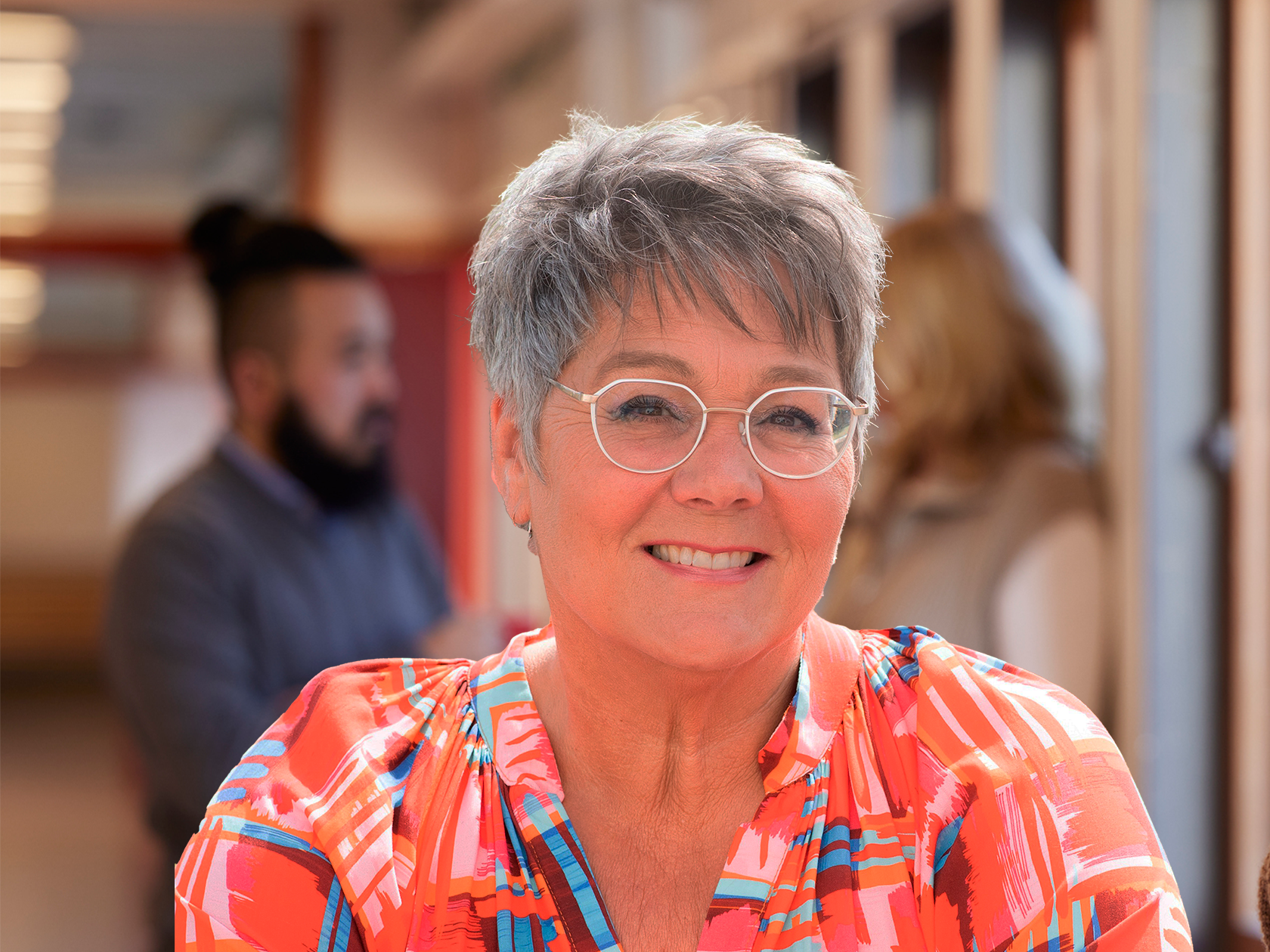 Lärare som ler mot kameran med vuxna i bakgrunden