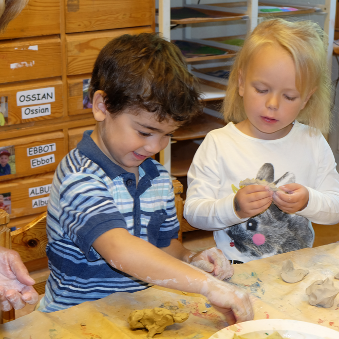Förskolebarn som leker med lera