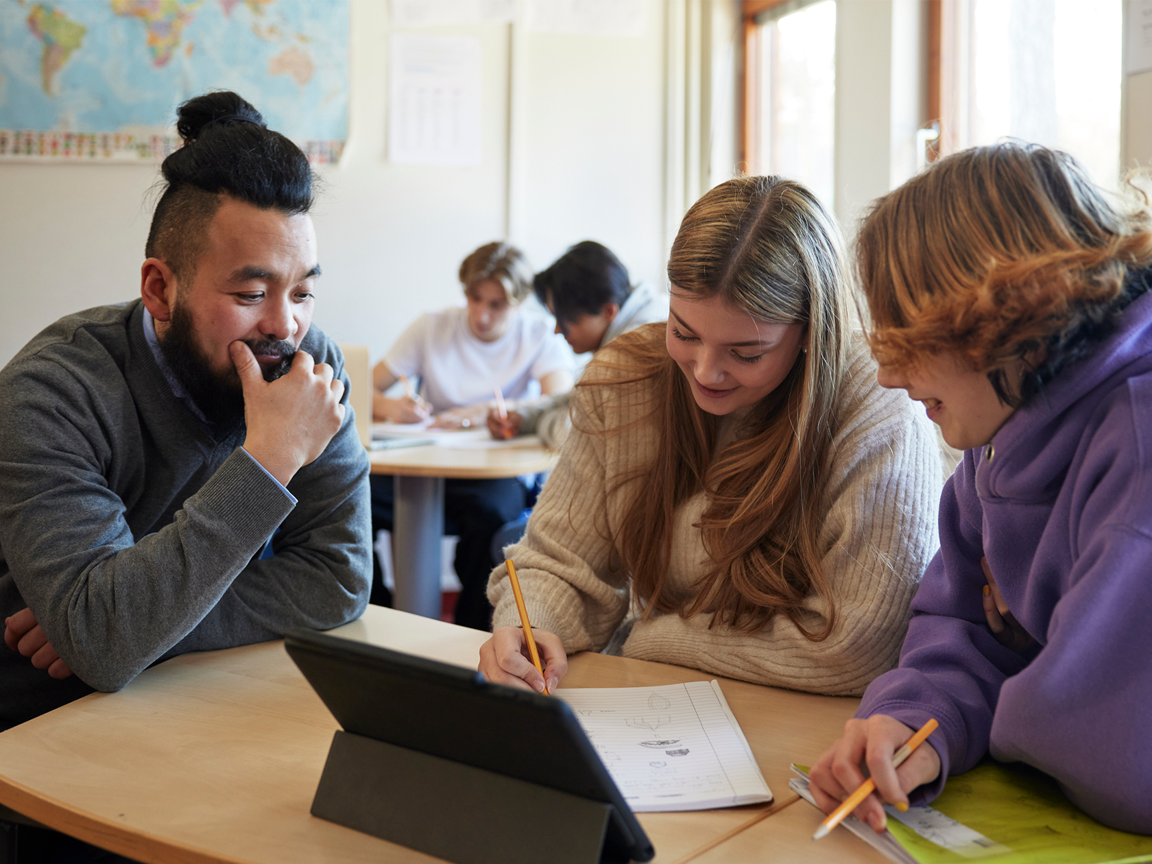 Lärare sitter och tittar på elev som arbetar